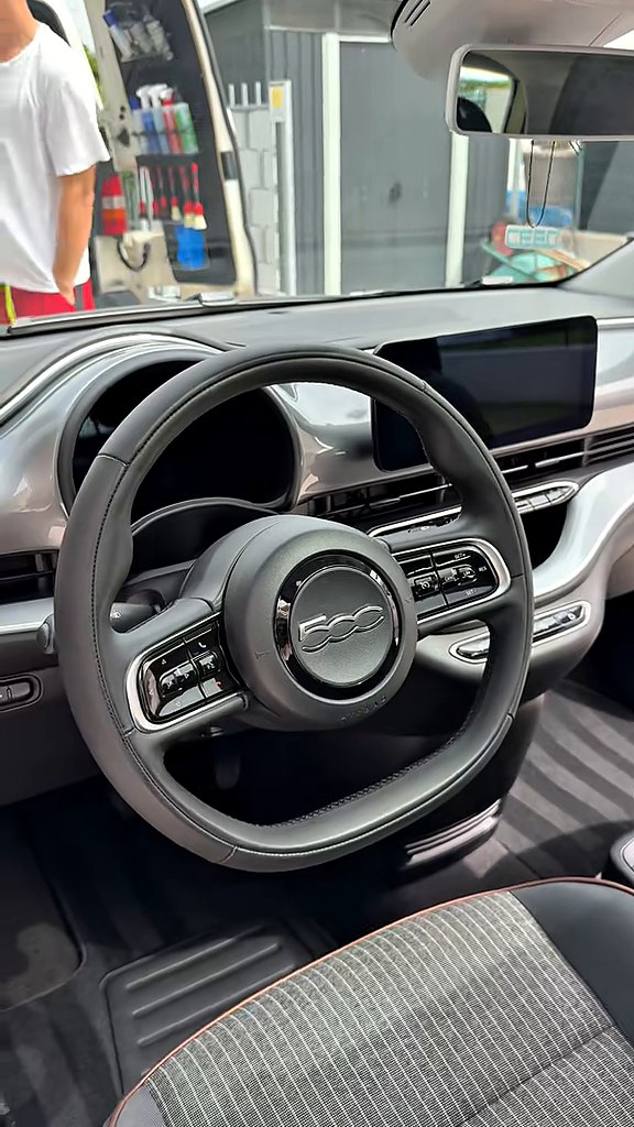Abitacolo di una Fiat 500e pulito, con volante e cruscotto